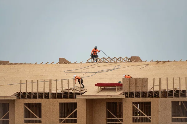 Roof construction. Roofer on roof structure. Construction Worker on Top of the Wooden House Frame. Worker roofer builder working on roof at construction site. Construction crew working on the roof