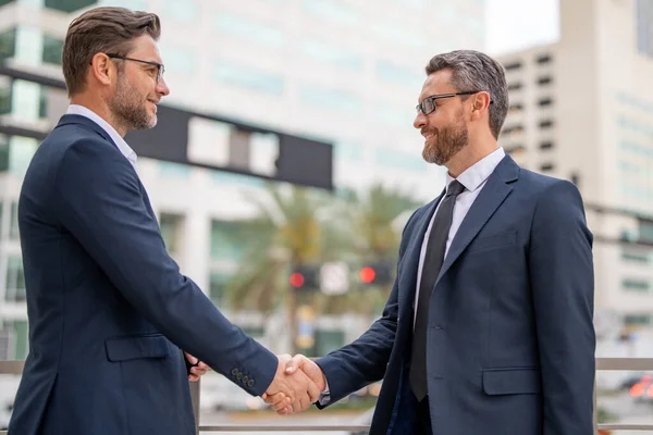 Businessman handshake with partner. Welcome business. Two businessmen shaking hands. Business men in suit shaking hands outdoors. Handshake between two businessmen