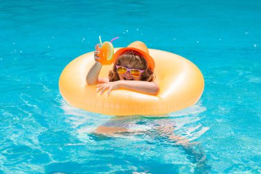 Havuzda kokteyl var. Çocuk bir meyve içeceğiyle yüzme havuzunda dinleniyor. Yaz tatili