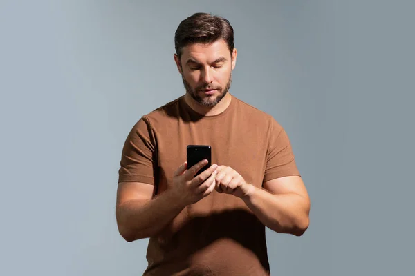 Portrait of a cheerful man using mobile phone isolated over studio background. Caucasian man using smart phone cellphone for calls, social media, mobile app. Online chatting. Guy talking on the phone