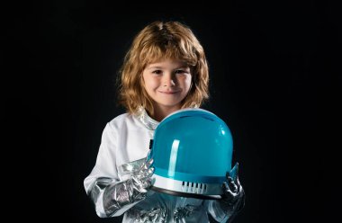 Miğferi rüya gibi görünen küçük astronotun yakın plan yüzü. Uzay kıyafetli küçük çocuk kameraya gülümsüyor. Çocukların başarısı, lideri ve kazanan konsepti.