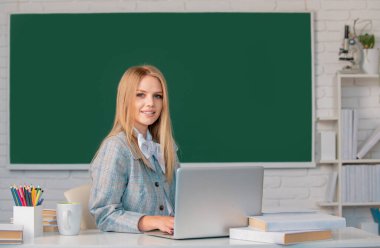 Sınıfta tahtadan arkaplanı olan genç, sarışın bir üniversite öğrencisinin portresi.