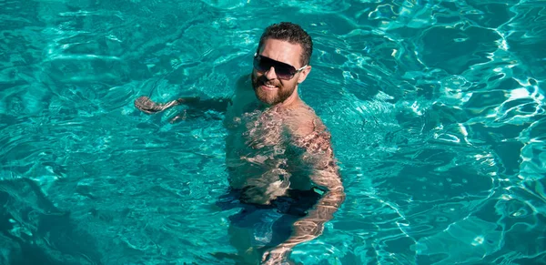 Guy in pool water. Spa resort. Summertime vacation. Summer man. Pool resort. Handsome man in swimmingpool