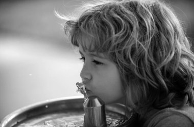 Dışarıdaki çeşmeden su içen çocuk portresini kapatın.