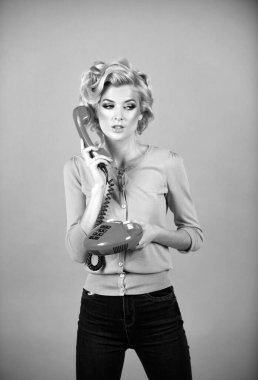 Retro telefondan konuşan genç bir kadın. Klasik telefon ahizesi olan bir kadın. Retro telefon kulaklıklı kız stüdyoda pembe arka planda izole edilmiş.