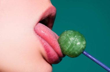Pembe dudakları olan, lolipop tutan seksi bir kadın ağzı, güzellik kapanışı. Seksi kız lolipopu yaladı. Güzellik konsepti, yakın plan.