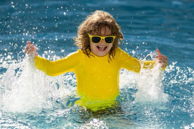 Havuza su sıçratan heyecanlı çocuk. Küçük çocuk mavi yüzme havuzunda su sıçratıyor. Havuzda yüzen ve su sıçratan tatlı çocuk. Su sıçratan ve havuz başında eğlenen çocuk