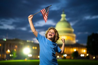 Komik çocuk Amerikan bayrağını tutuyor. Vatansever bayram. Washington 'da Amerikan bayrağı taşıyan çocuk. ABD 'li çocuklar 4 Temmuz' da bağımsızlıklarını kutluyorlar. Amerikan Bayrağıyla Şaşırmış Amerikalı çocuk