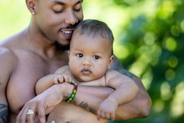 Çok ırklı ebeveynler ve karışık ırk bebekleri. Karışık ırk, çok ırklı, açık havada çekilmiş aile portresi. Çift ırklı bir bebek. Çok güzel bir aile. Çok ırklı aile bahçede birlikte eğleniyor.