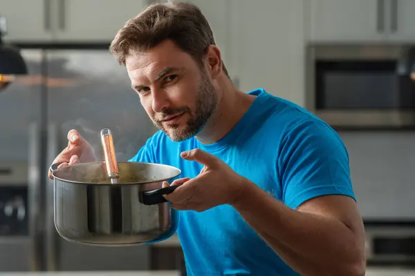 Cooking food at home. Man in kitchen preparing a meal. Male cook preparing food in kitchen at home. Chef cooking meal. Man cooking food, kitchen pot, food plate. Man preparing soup on kitchen interior