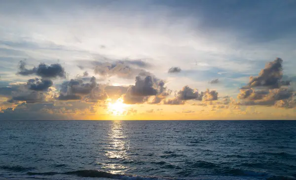 Gün batımı deniz manzarası. Sakin dalgalarla renkli sahil gündoğumu. Doğa deniz göğü. Güzel tropikal plajın doğa manzarası. Mavi gökyüzüne ve denize karşı farklı renkte bulutlarla gün doğumu