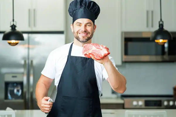 Chef cooking raw meat fillet in the kitchen. Restaurant menu concept. Male portrait of chef man hold meat in the kitchen. Raw meat fillet for advertising. Fork veal filet, roasting steak. Raw steak