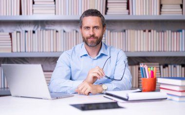 Kütüphane sınıfındaki öğretmenin portresi. Üniversite kütüphanesinde yakışıklı bir öğretmen. Öğretmenler Günü. Öğretmen ders veriyor. Kütüphanede öğretmen. Üniversite kütüphanesinde ders veriyorum.