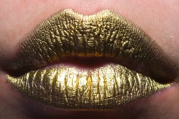 Gold lips. Gold paint on mouth. Golden lips. Luxury gold lips make-up. Golden lips with creative metallic lipstick. Gold metal lip. Sensual woman mouth, clse up, macro