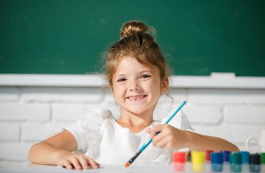 Okuldaki çocuk boyalarla resim çiziyor. Çocukların yaratıcılığı. Resim dersi, resim dersi.