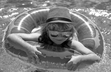 Yüzme havuzunda şişme oyuncak yüzüğü olan küçük bir çocuk. Çocuklar yaz tatili. Şamandırada çocuk için yüz. Plaj denizi ve su eğlencesi