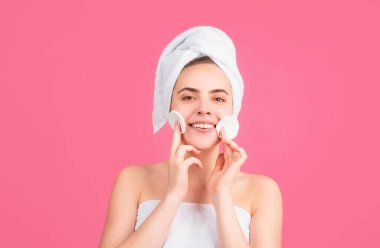 Temiz tenli, gülümseyen güzel bir kız. Yüz bakımı. Kozmetik güzellik ve kaplıca. Yüzüne krem sür, kadın başını havluya sar ve cildine krem sür.