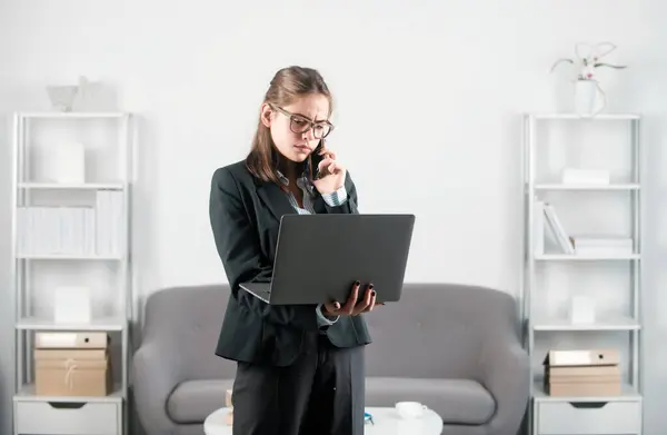 Young businesslady at workplace in the office. Secretary woman in formal wear working on project at modern office. Secretary taking a call