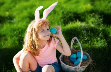 Paskalya yumurtası avlayan çocuk. Paskalya yumurtası ve tavşan kulaklı çocuk..