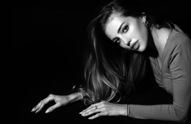 Siyah üzerine şehvetli pozlar veren seksi kız. Siyah arka planda ışığı olan zarif bir kadının portresi. Karanlıkta güzel bir kadın yüzü