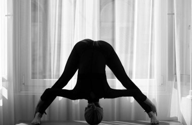 Evinde yerde esneme egzersizleri yapan bir kadın. Kadın esniyor. Genç kız yoga yapıyor, egzersiz yapıyor, spor yapıyor.