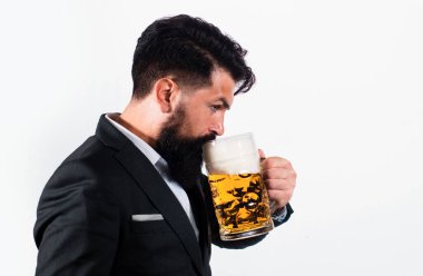 Klasik takım elbiseli adam bira içiyor. İş kıyafetli sakallı adam mutlu ve memnun görünüyor. Yüksek bardakta bira içen adamın portresi.