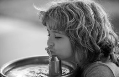 Dışarıdaki çeşmeden su içen çocuk. Susamış çocuk