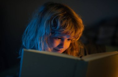 Çocuk kitaptan masal okuyor. Oturma odasında hikaye kitabındaki resimleri izleyen küçük bir çocuk. İlkokul için ödev yapan bir çocuk. Çocuklar çalışır