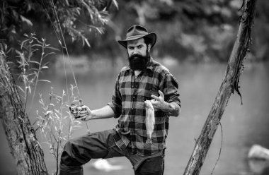 Balıkçının dağ nehrinde olta atarak balık tutarken portresi. Ormandaki nehirde alabalık avlayan bir balıkçı. Bahar tatili