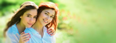 Açık havada kadın kız arkadaşlarla bahar pankartı. Parktaki güzel kadın. İki güzel kızıl kız. Neşeli kardeş, kavramı kucakla.