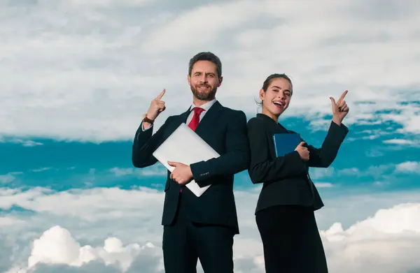 Portrait of a business couple with pointing finger. Young confident businesspeople. Secretary and boss. Business people in suit outdoor. Businessman and businesswomen