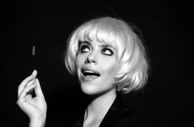 Modellik yapan kaşlar, güzel yüzlü büyüleyici bir bayan, sağlıklı ve temiz bir cilt, elinde fırça ve kaşlarını boyuyor. Siyah stüdyo arka planında izole edilmiş kadın portresi