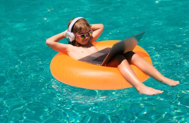 Yaz çevrimiçi teknoloji. Yaz tatilinde dizüstü bilgisayarla çalışan çocuklar. Bilgisayar kullanan küçük bir serbest çalışan, yüzme havuzunda çalışan.