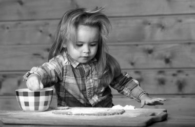 Bebek hamuru hazırlıyor, mutfakta kurabiye pişiriyor.