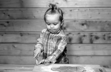 Küçük çocuk yemek yapıyor, ahşap mutfakta unla oynuyor.