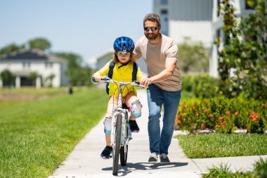 Babalar Günü. Babalar gününde yolda bisiklete binen baba ve oğul. Arkadaş canlısı aile kavramı. Ebeveynler ve çocuklar arkadaş oluyor. Baba ve oğlu dışarıda bisiklet sürüyor. Önce çocuk bisikleti