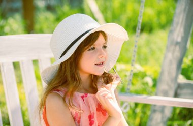 Çocuk salıncakta oynuyor. Sıcak havalarda çocuklar için sağlıklı bir yaz etkinliği. Küçük çocuklar sallanıyor. Şapkalı güzel bir kızın hayal ettiği portreyi yakından çek. Rüya gibi çocuklar.