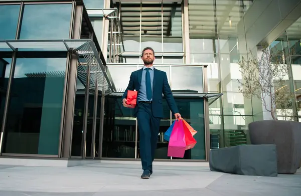 Business man doing shopping in the city. Portrait of businessman in suit with shopping bags