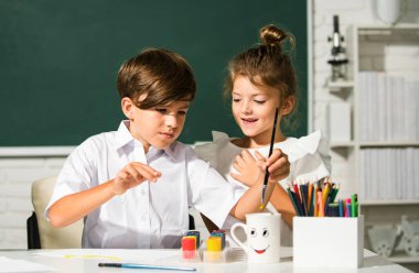 Çocuklar erkek ve kız kardeşler okulda ya da anaokulunda renkli kalemlerle güzel çizim yapıyorlar. Çocukluk eğitimi, çocukların sanatsal becerileri.