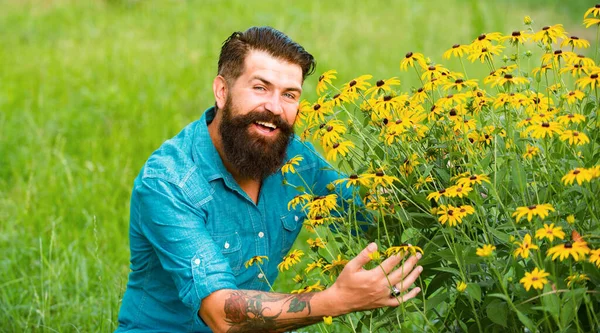 Smiling man with flowers. Spring mood. Sunny portrait. Carefree and positive thinking. Rudbeckia flower