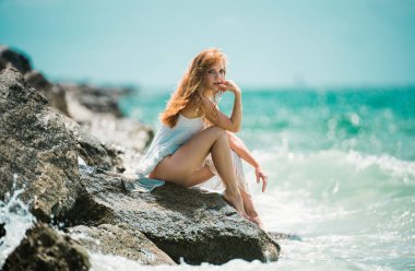 Kumsalda oturan şehvetli genç bir kadın. Kadınlar deniz kenarında oturup, tatilin ve yaz tatilinin tadını çıkarırlar.