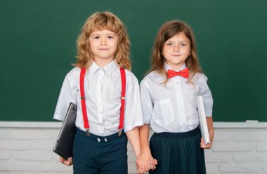 Okul arkadaşları birlikte öğreniyor. Okuldaki kız öğrenci ve erkek öğrenci sınıfında. Çocuklar sınıfta karatahtanın yanında el ele tutuşuyorlar. Arkadaşlık ve sınıf arkadaşı kavramı. En iyi okul arkadaşları