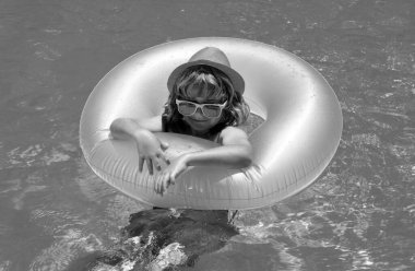 Yüzme havuzundaki çocuk şişme halkada. Çocuk turuncu şamandırayla yüzüyor. Su oyuncağı, çocuklar için sağlıklı açık hava sporları. Çocuklar plaj eğlencesi