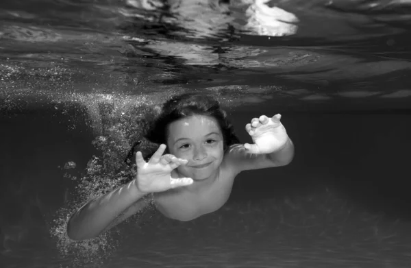 Cute boy swimming underwater in shallow turquoise water at tropical beach. Child swim and dive underwater in the swimming pool. Underwater children