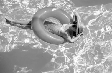 Yaz tatili. Yüzme havuzunda şişme dairede mayo giymiş bir kadın.