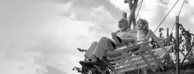 Yaşlı büyükbaba ve küçük torun bahçede sallanıyor. Büyükbaba ve torun parkta salıncakta oturuyor. Büyükbaba ve torun, bahar bayrağı