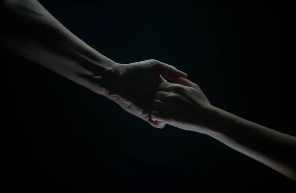 Helping hand outstretched, arm on salvation. Close up strong hand. Two hands, helping arm of a friend, teamwork. Rescue, power, helping gesture or hands. Black background