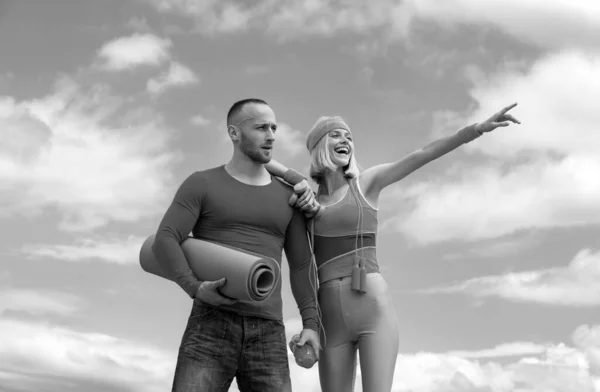 Portrait of athletic young happy couple holding dumbbells and fitness mat outdoor