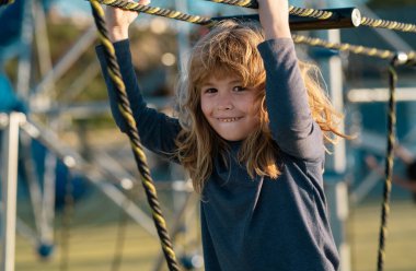 Çocuk ağa tırmanıyor. Çocuk dışarıda oyun oynuyordu. Çocuklar okulda ya da anaokulunda oynarlar. Aktif çocuk renkli kayıyor ve sallanıyor. Çocuklar için sağlıklı yaz etkinliği