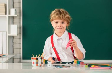 Boyama kalemleriyle resim yapan çocuk, erken gelişim resimleriyle resim yapan çocuk. Resim dersi alan çocuk resim ödevi yapıyor. Çocuk ilkokulda resim çiziyor.
